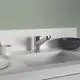 Küchenarmatur in Chromoptik an einer weißen Arbeitsplatte, daneben Geschirr und eine Schüssel, angedeuteter Stil von Ideal Standard. Helle Wand im Hintergrund.